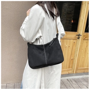 Détail du sac hobo en daim noir avec coutures blanches et fermeture éclair en métal
