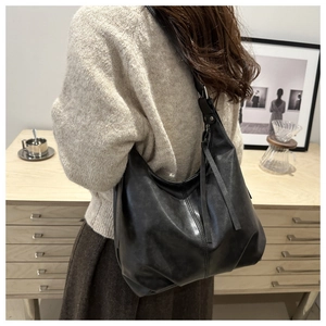 Detail view of large black retro leather tote bag featuring stylish side tassel and soft texture