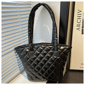 Detail of glossy black quilted puffer tote bag with classic diamond stitching and shiny finish