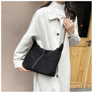 Détail du sac bandoulière noir mat avec surpiqûres blanches et tirette de zip tressée