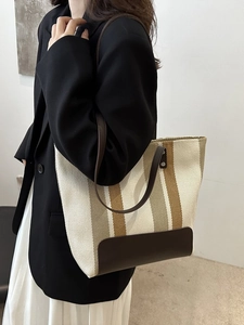 Chic striped canvas tote bag with brown leather straps shown on a business casual model