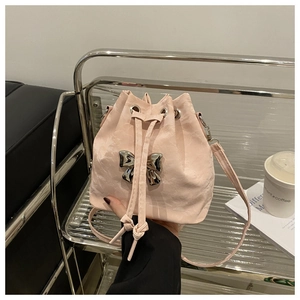 Detailed macro view of pink pleated bucket bag with metallic bow and drawstring closure