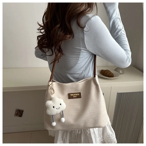 Détail du sac à main gaufré blanc cassé avec bandoulière en cuir brun et breloque peluche