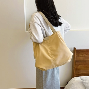 Detail view of large ginger yellow nylon tote bag with fashion label on shoulder