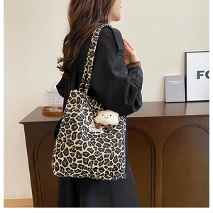 Detail of leopard print canvas tote bag with a white fluffy pendant accessory