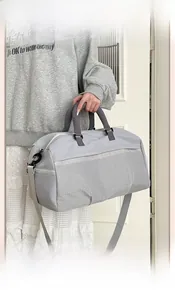 Detail of light grey travel bag with front mesh pocket and adjustable shoulder strap