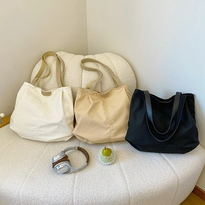 Detailed view of three canvas tote bags in beige, khaki and black colors on a soft stool