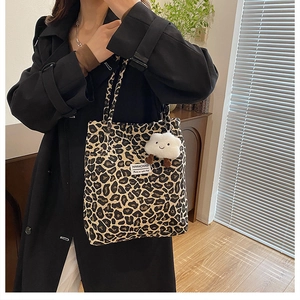 Detail of leopard print tote bag with plush cloud charm and white woven brand label