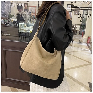 Détail du sac hobo en daim beige crème avec bandoulière en cuir brun et anneau doré