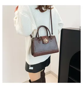 Détail d'un sac cabas marron rétro avec texture crocodile et boucle dorée en forme de soleil