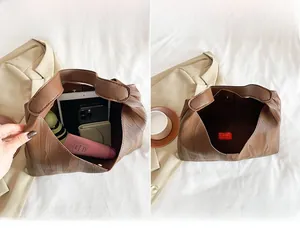 Detail view showing large interior capacity of brown tote bag with phone and umbrella