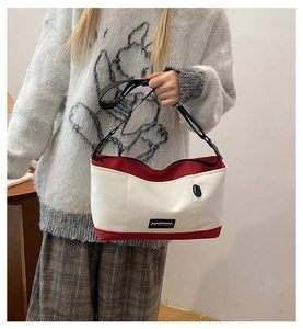 Detail view of red and white canvas crossbody bag with adjustable strap and zipper closure