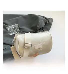 Detail of embroidered beige boston bag with floral patterns and a wide fabric strap