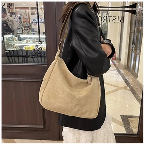 Détail du grand sac cabas en daim beige avec bandoulière en cuir marron sur le modèle