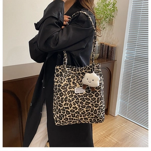 Close-up of leopard print canvas tote bag with a white plush cloud charm and label