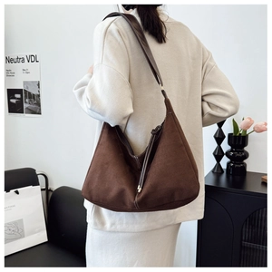 Détail du sac hobo en daim marron avec bandoulière en cuir et surpiqûres blanches contrastées