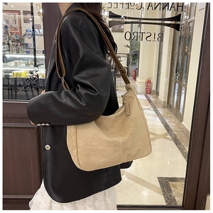 Vue détaillée du sac hobo beige avec bandoulière en cuir marron dans un café chic