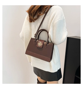 Détail du sac cabas marron vintage avec texture crocodile et boucle fleurie en métal