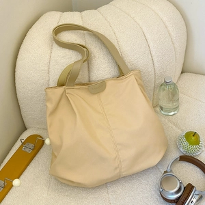 Detail view of cream canvas tote bag showing soft nylon texture and fashion label on a sofa