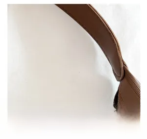 Detailed macro view of the brown leather shoulder strap with reinforced stitching and texture