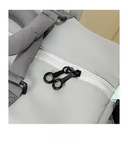 Close-up of smooth black double zippers and metal hardware on a grey fitness travel bag