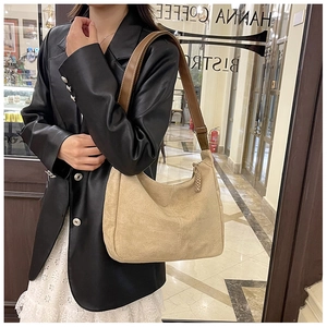 Vue détaillée du sac hobo en daim beige avec bandoulière en cuir brun et coutures