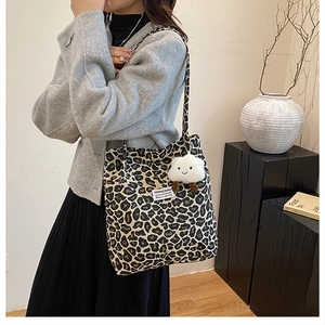 Detail of leopard print tote bag with white fluffy cloud charm and branding label