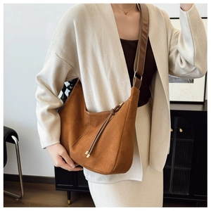 Détail du sac hobo en daim marron avec large bandoulière en tissu et fermeture éclair
