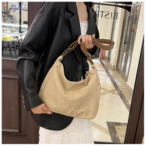 Détail d'un sac cabas en croissant avec coutures verticales et poignée en cuir marron