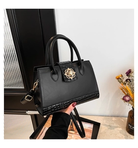 Détail du sac noir effet crocodile avec boucle fleur dorée et doubles poignées de main