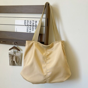Close-up detail of the metal FASHION logo on a beige canvas tote bag handle