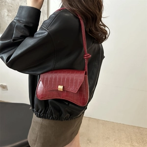Deep red crocodile embossed hourglass crossbody bag with gold buckle on female model