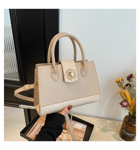 Détail du cabas en cuir beige avec garniture dorée florale et une bandoulière amovible