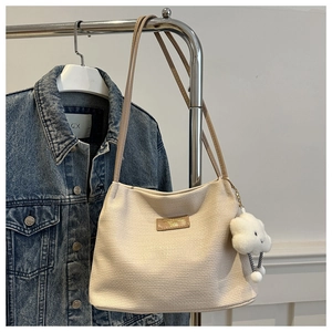 Détail du sac cabas crème texturé avec pendentif nuage sur un support métallique