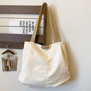 Detail of cream canvas tote bag with brown leather FASHION patch and wide strap
