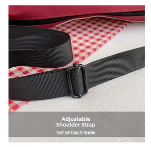 Close-up of adjustable black fabric shoulder strap with buckle on red canvas crossbody bag