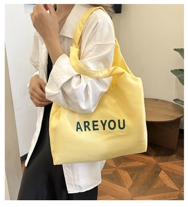 Gros plan du grand sac cabas jaune avec inscription AREYOU verte et texture en toile robuste