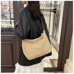 Détail d'un sac bandoulière en toile kaki avec une breloque de fermeture éclair tissée