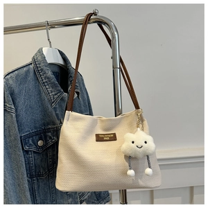 Détail du cabas tissé blanc cassé avec étiquette en cuir marron et breloque en peluche