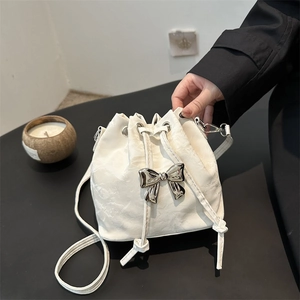 White drawstring bucket bag with pleated texture and silver metal bow detail
