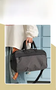 Fashionable travel bag in black and plaid pattern held by model for gym or short trips