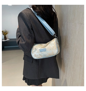 Detail of light blue embroidered crossbody bag showing fit and floral landscape pattern