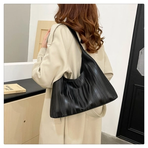 Close-up of minimalist black tote bag with unique wave texture and wide shoulder strap