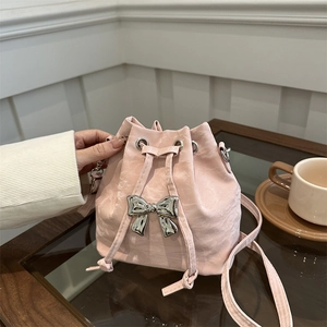 Pink drawstring bucket bag with silver bow accent and adjustable shoulder strap
