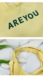 Gros plan sur le sac fourre-tout jaune avec lettrage vert et poignées épaisses robustes