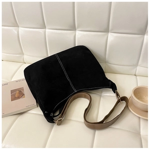 Détail d'un sac fourre-tout en daim noir avec surpiqûres blanches et bandoulière marron