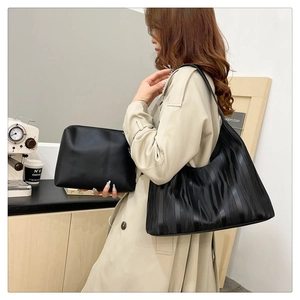 Detail view of black tote and clutch set with textured waves and modern leather finish