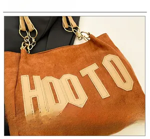 Détail du sac cabas en daim marron avec lettres brodées HOOTO et bandoulière à anneau métal