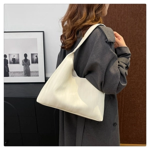 Close-up of white pleated hobo tote bag texture on female model in dark coat