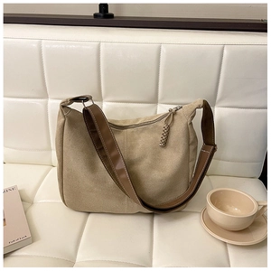 Gros plan du sac cabas beige avec bandoulière marron sur un canapé blanc
